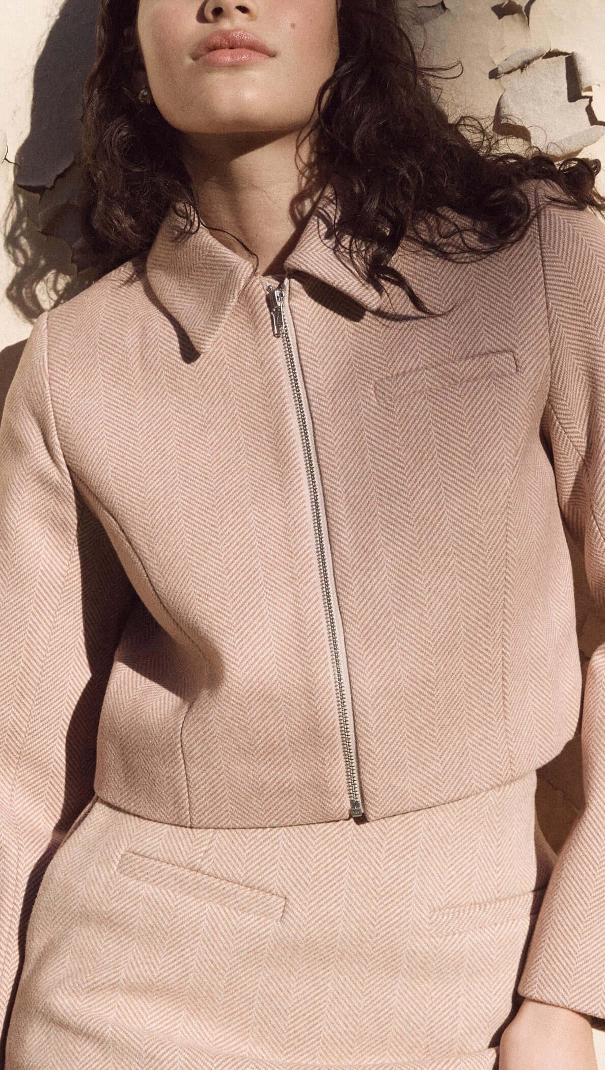 Audrey Herringbone jacket in brown shade, cropped silhouette with zipped collar, styled with matching skirt.