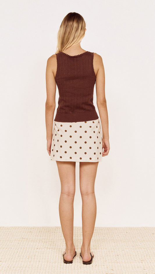Model wearing Cotton Pointelle Knit Tank in Chocolate with a polka dot skirt from the back on a neutral background.
