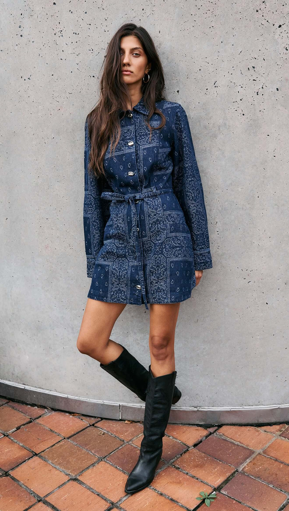 Model wearing a Paisley Jacquard Denim Shirt Dress with a collared neckline and waist tie, styled with knee-high boots.