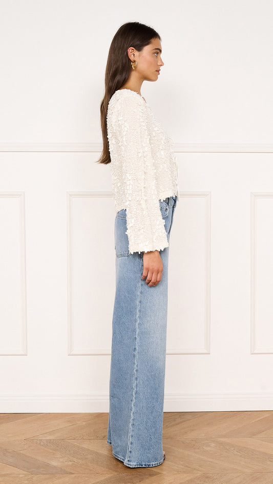 Flute Sleeve Sequin Tie Blouse in Cream styled with high-waisted jeans, showcasing a side view.