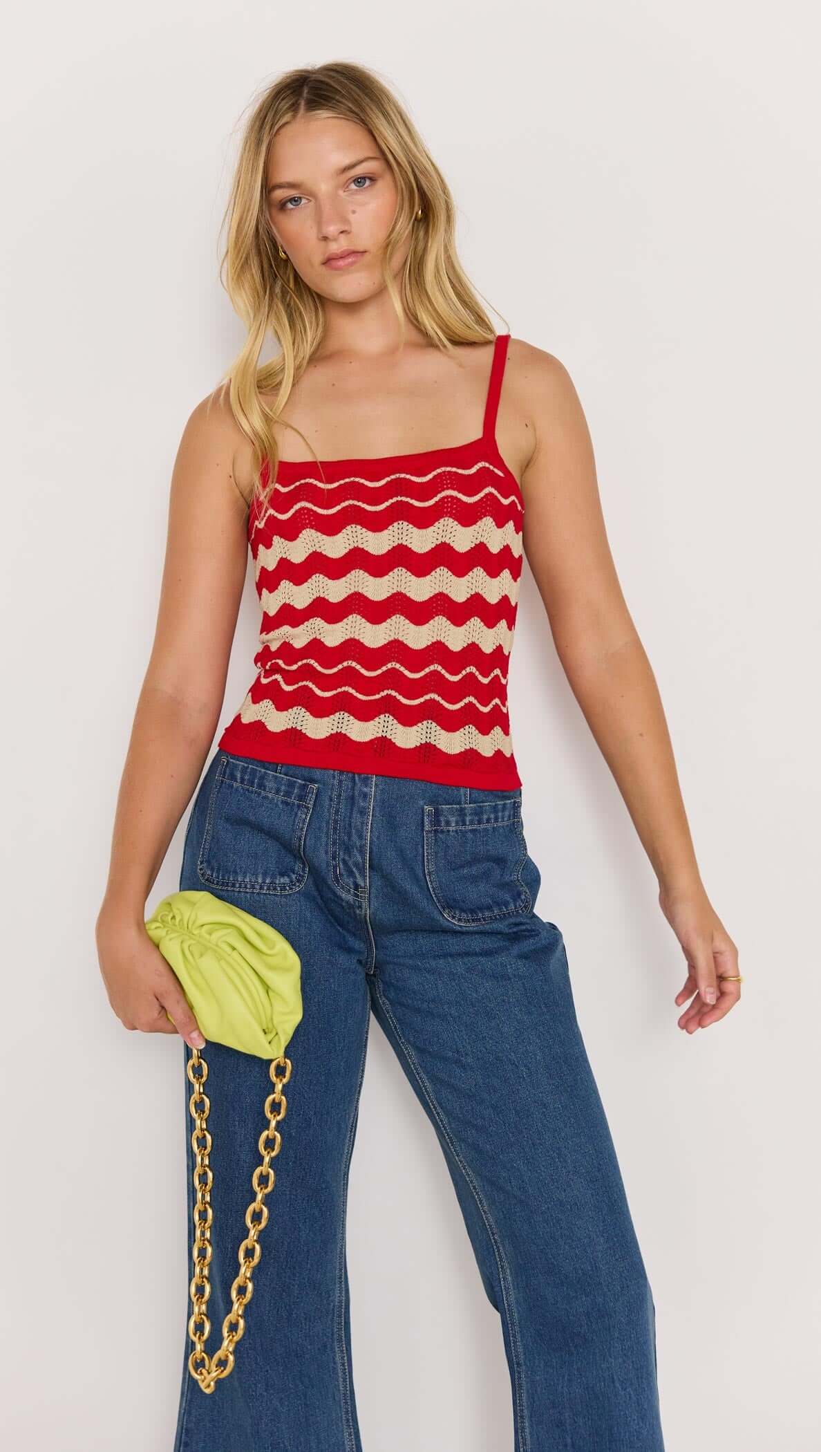 Model wearing a red and beige wave knit cami with scoop neckline and fixed straps, paired with denim jeans.