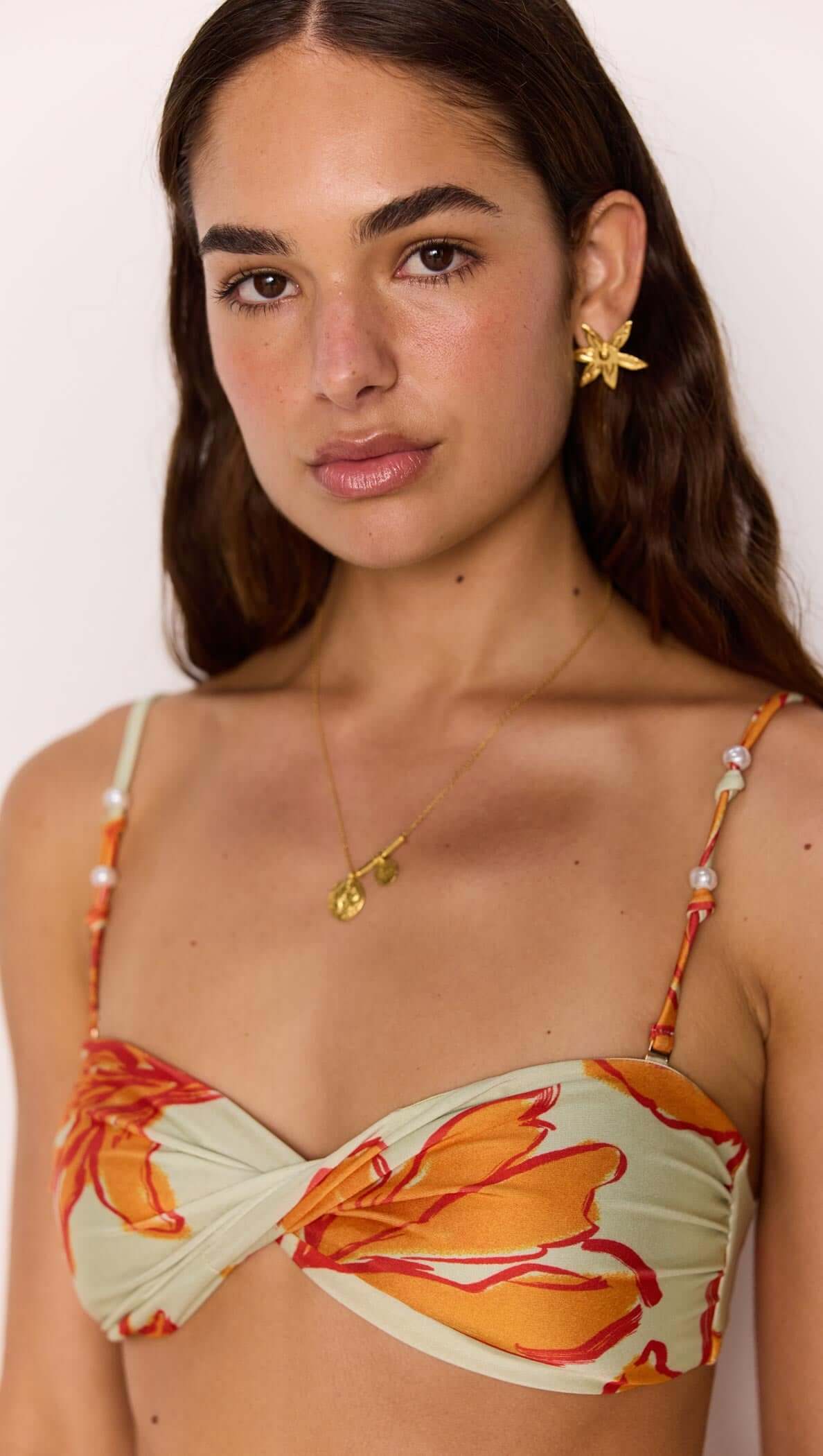 Model wearing a Green & Orange Twist Bikini Top with floral print and beaded straps.