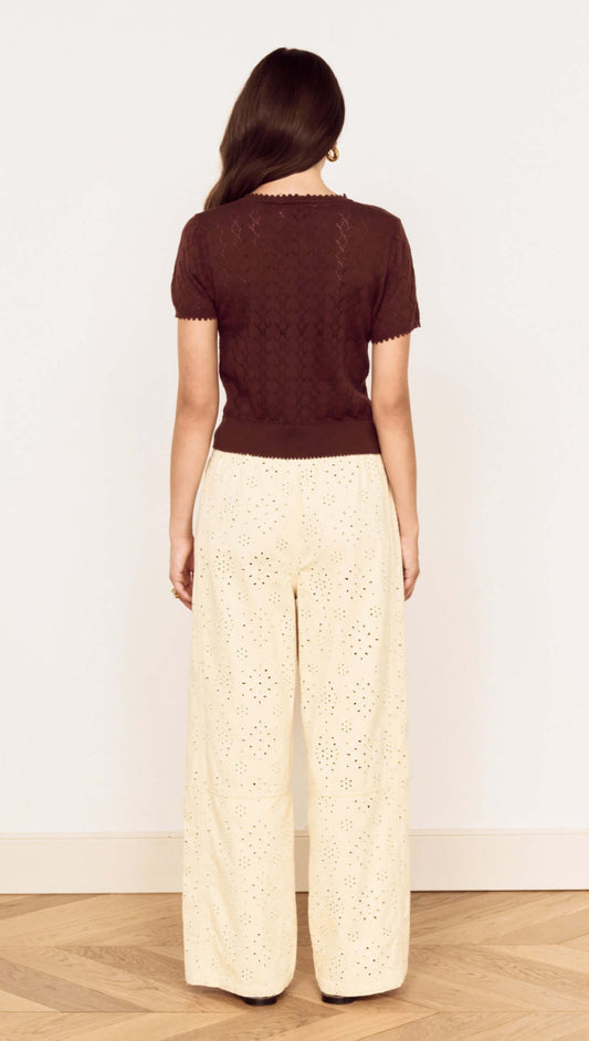 Back view of a model wearing a Brown Scallop Edge Knitted Tee with wide-leg eyelet trousers.