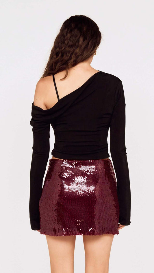 Model wearing a fitted black top with the Purple Sequin Mini Skirt, showcasing its sparkling deep burgundy sequins.