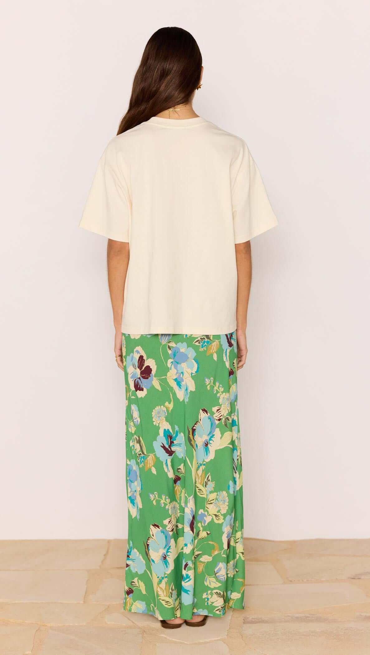 Back view of model wearing Ciao Bella Relaxed Cotton Oversized Tee with floral green maxi skirt.