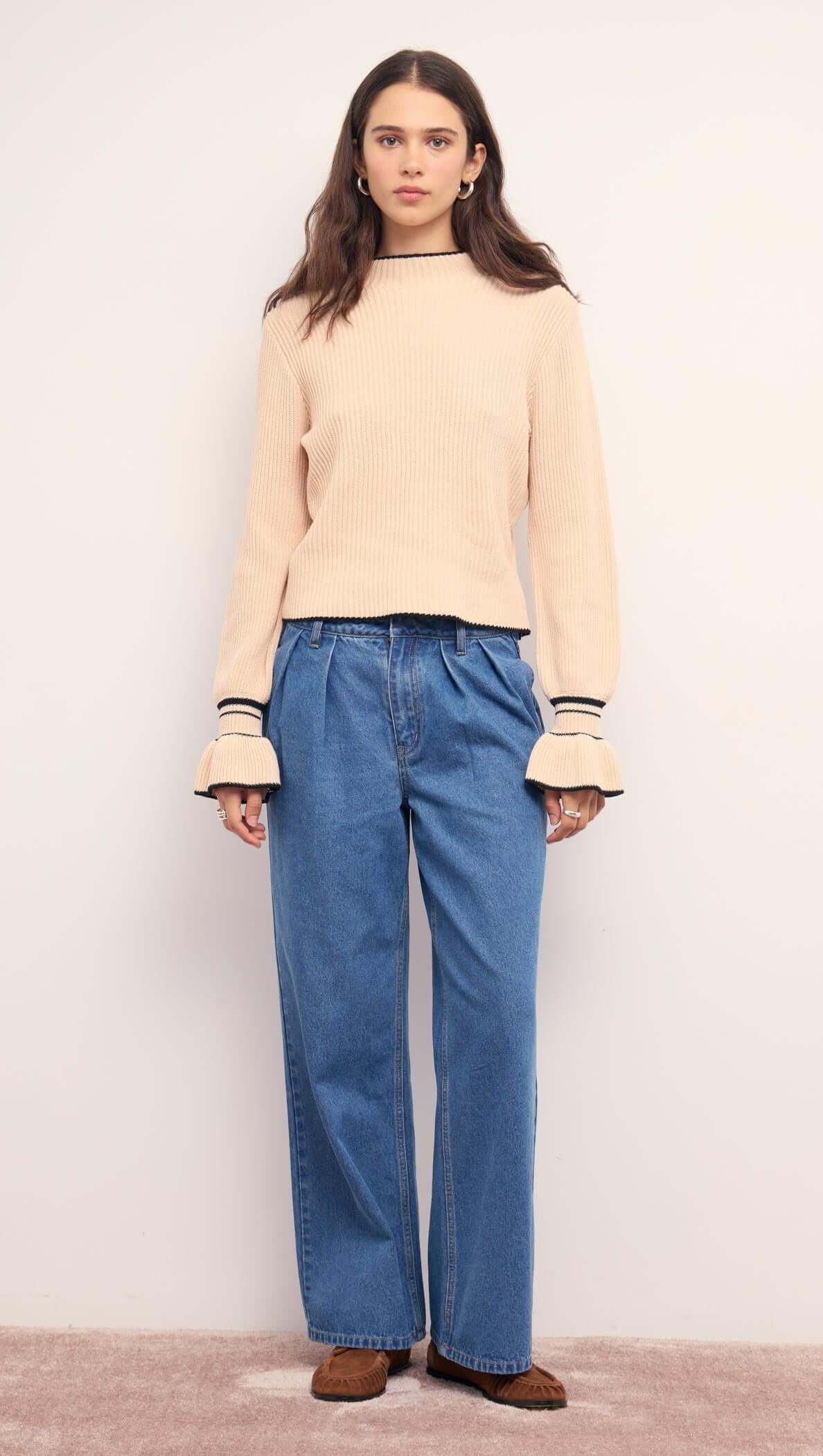 Model wearing a Cream Knit Top with Contrast Trim paired with relaxed denim pants.