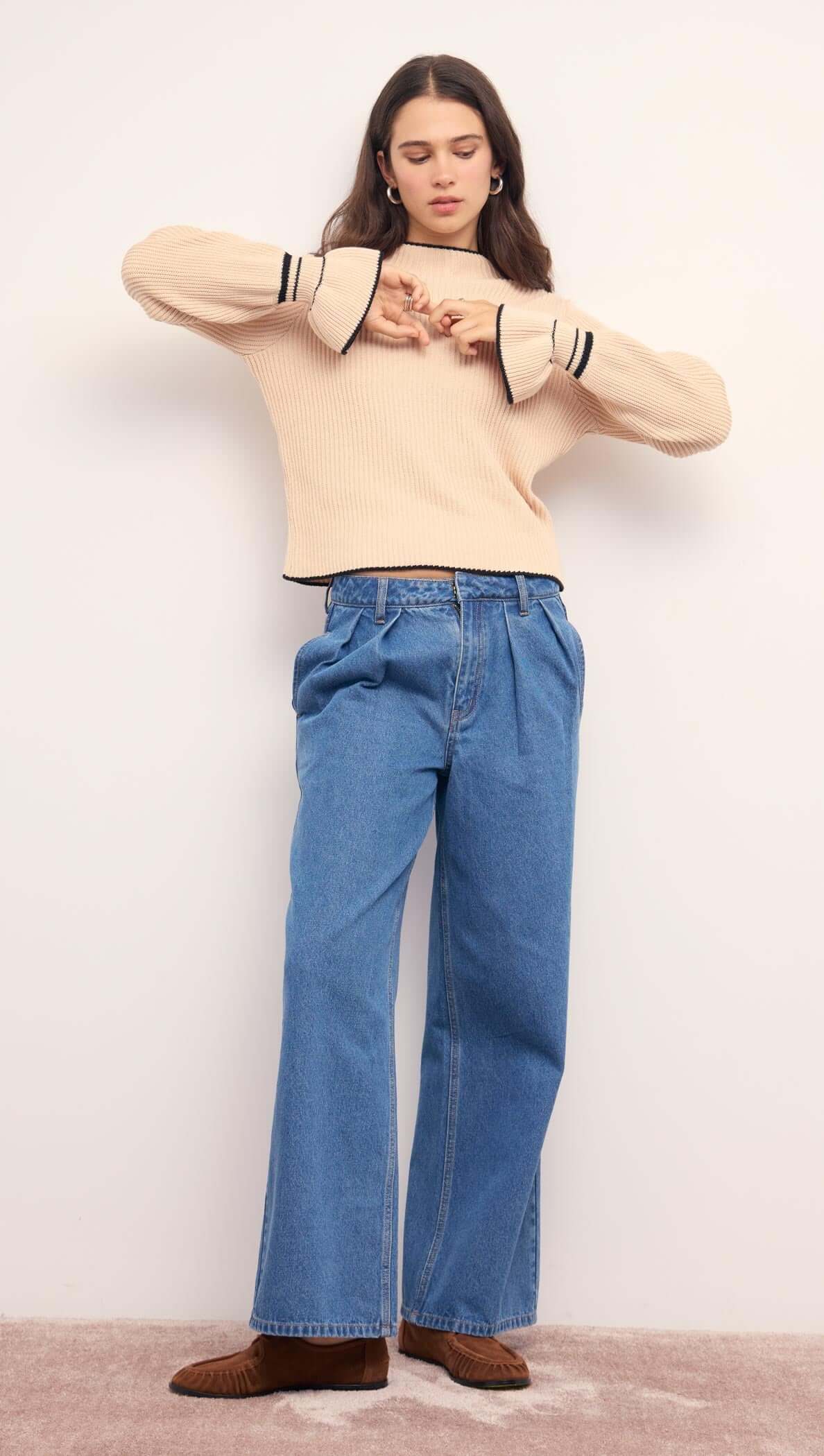 Cream Knit Top with Contrast Trim styled with wide-leg denim pants, showcasing flared cuffs and relaxed fit.