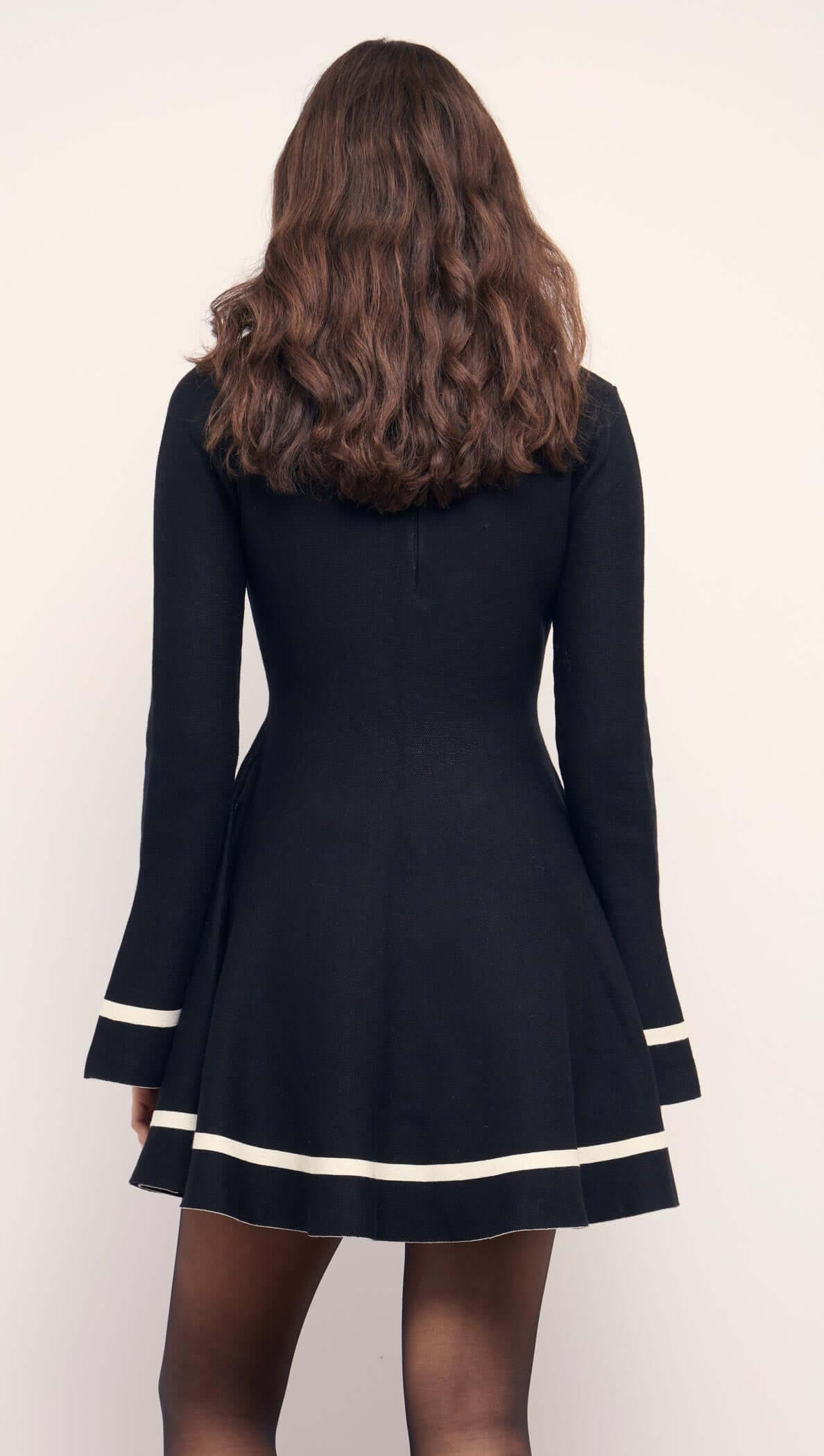 Black Peplum Knit Mini Dress With Contract Trim displayed from the back, featuring flared cuffs and modern trim.