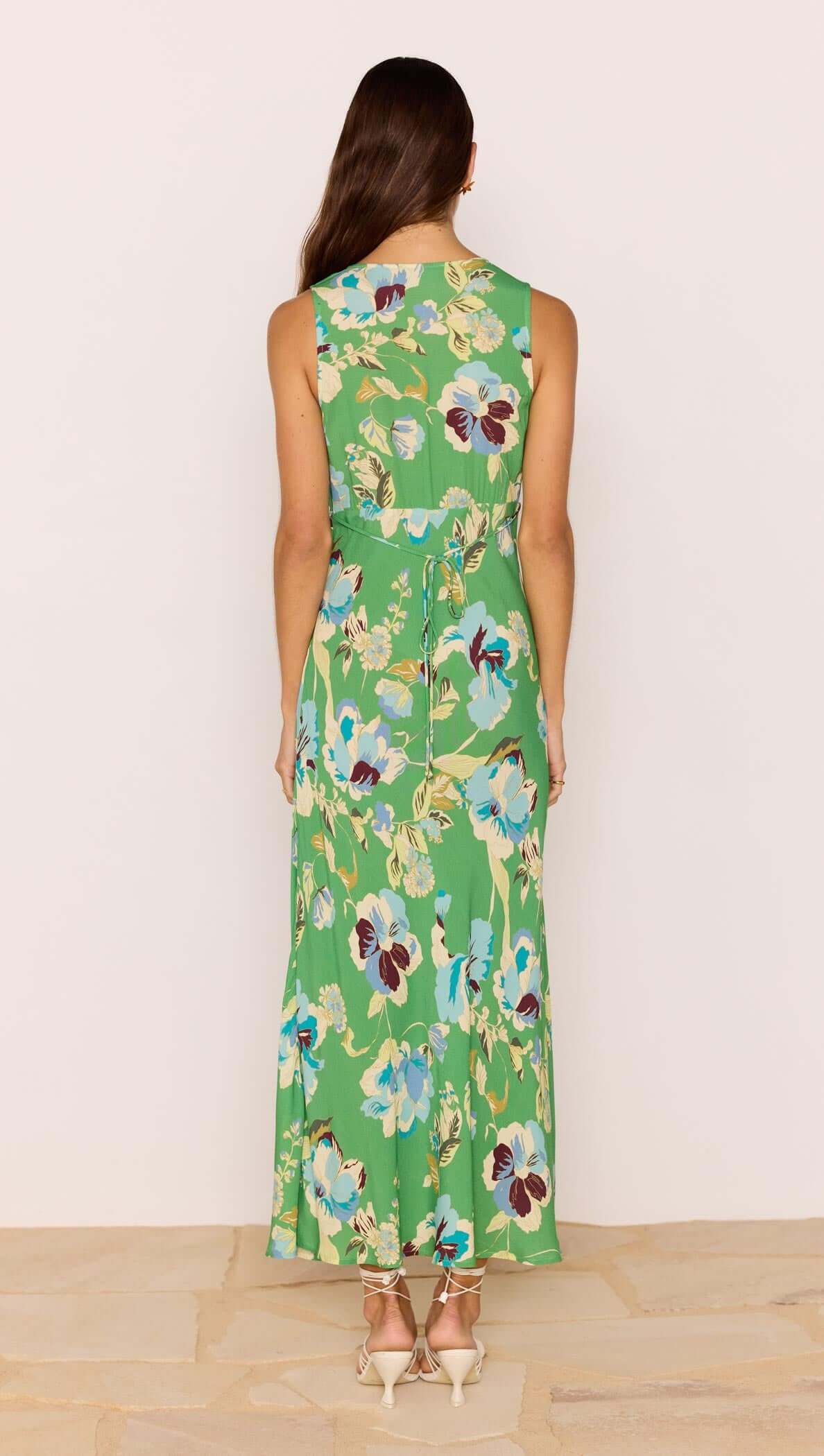 Back view of a model wearing the Green Floral Bias V-Neck Midi Dress showcasing its flowy design and vibrant floral print.