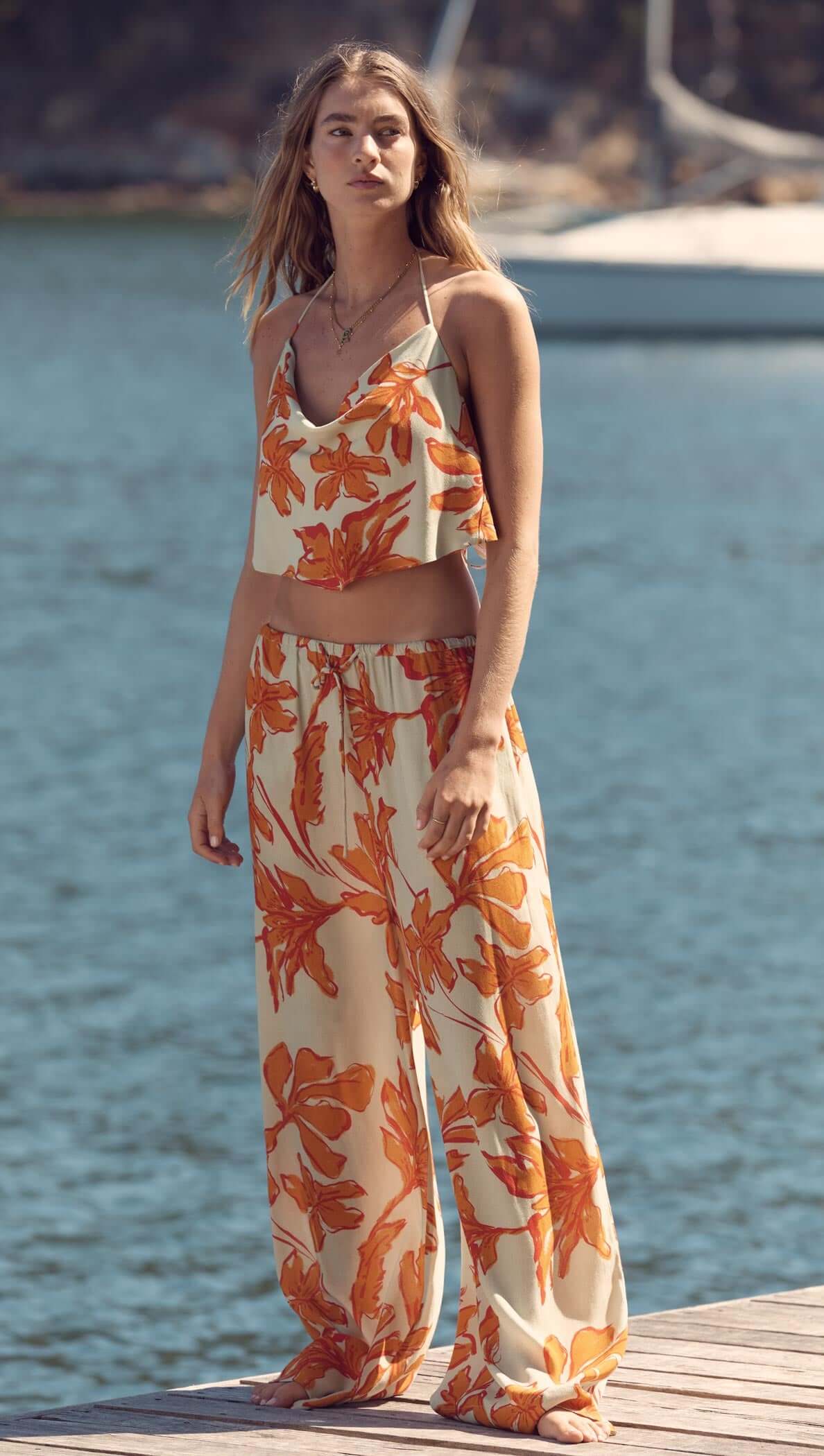 Woman wearing Green & Orange Floral Drawstring Wide Leg Pant by the water, showcasing a stylish summer look.