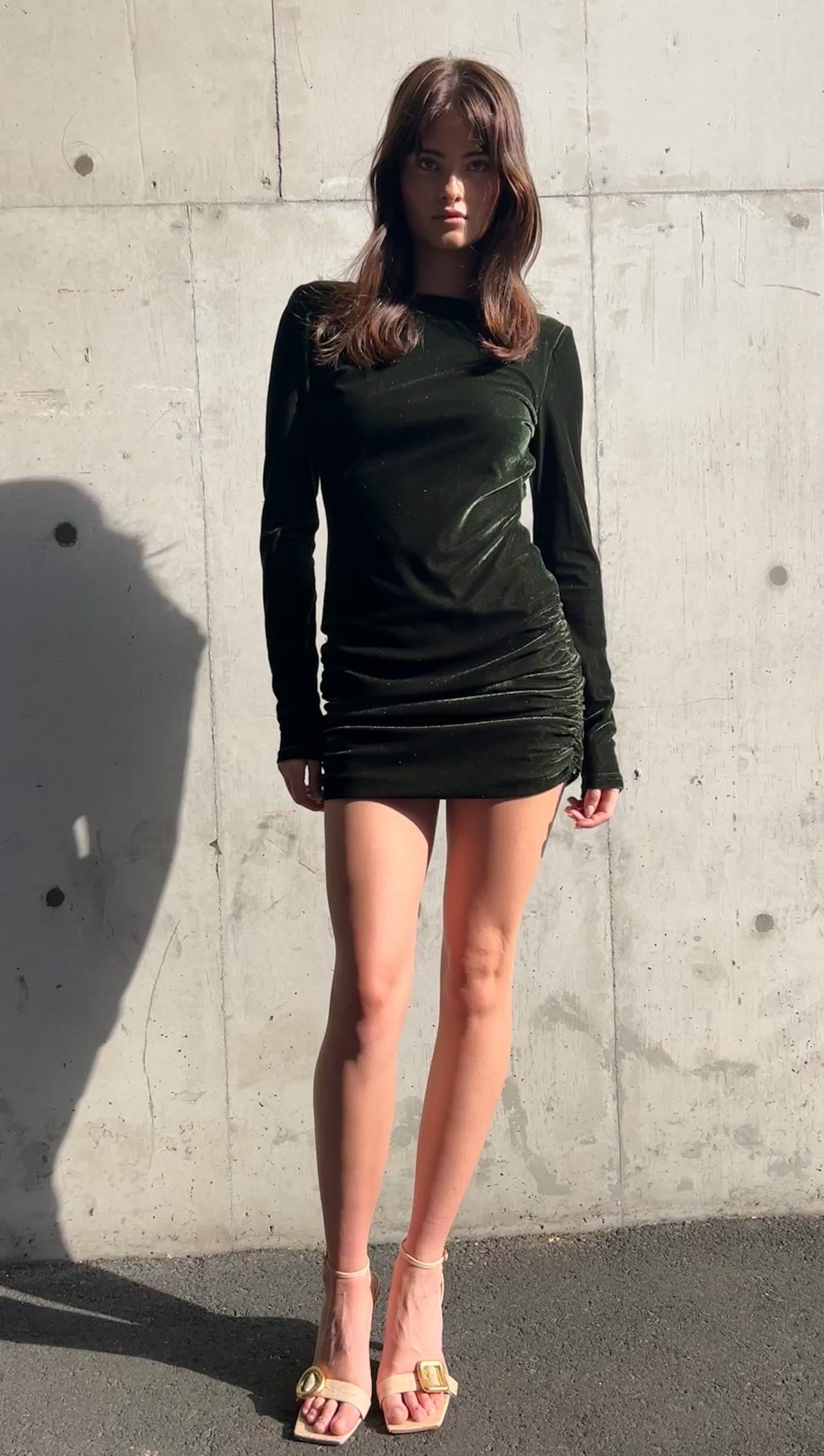Model wearing a Green Velvet Open Back Mini Dress with a ruched skirt and long sleeves.