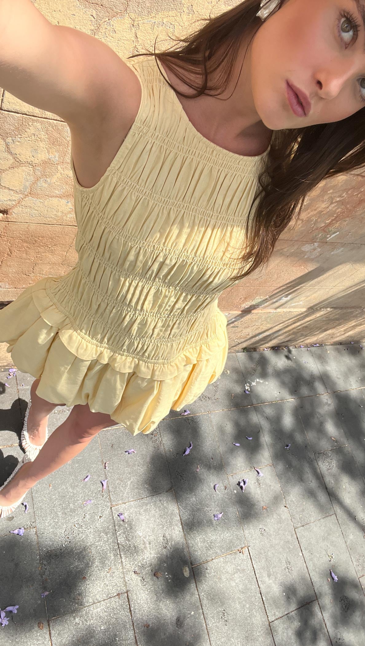 Butter Yellow Shirred Bubble Mini Dress worn outdoors, showcasing its shirred bodice and bubble hem skirt.