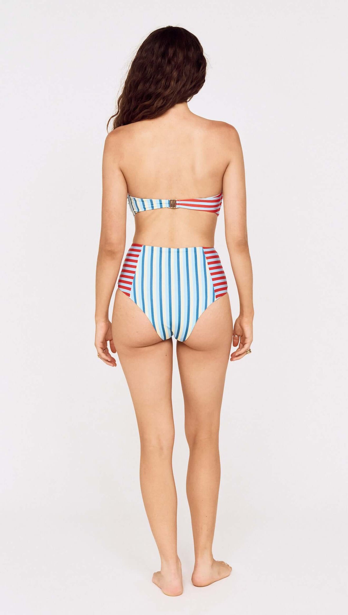 Back view of a woman wearing a Contrast Stripe High Waisted Bikini Bottom with colorful vertical stripes.