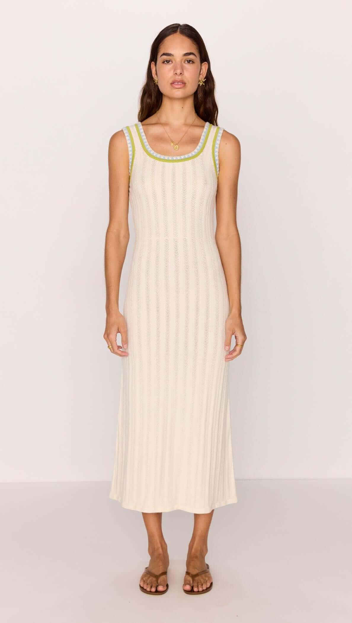 Model wearing a white knit midi dress with contrast green trim, showcasing a stylish summer look.