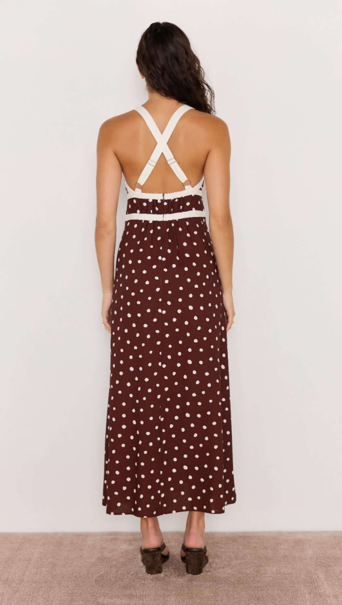 Back view of the Cedar Spot Cross Back Dress with chocolate brown polka dot pattern and white crossover straps.