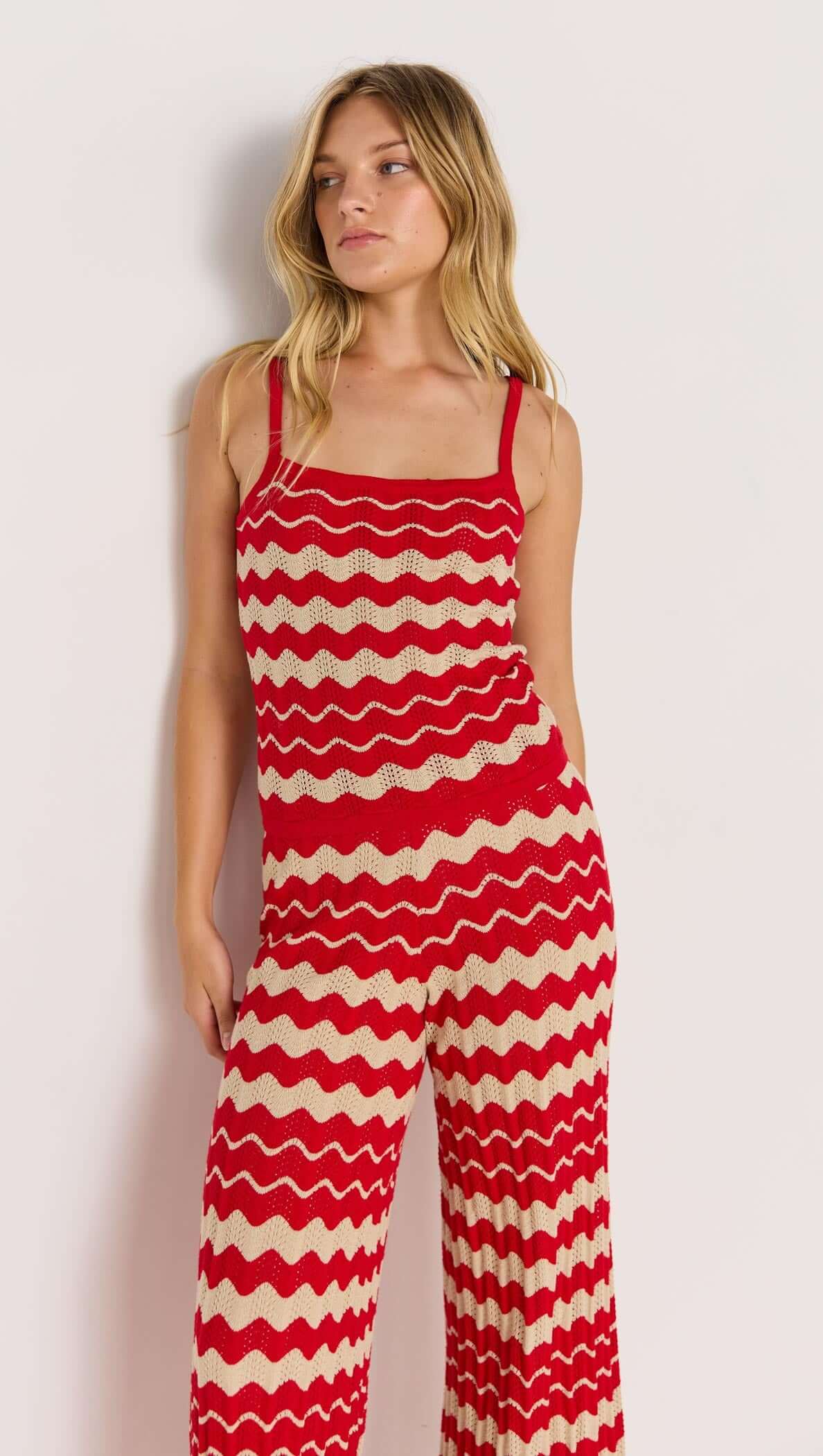 Model wearing WAVE STRIPE KNIT PANTS in red-beige, featuring relaxed leg, mid-rise fit, and soft stretch knit design.