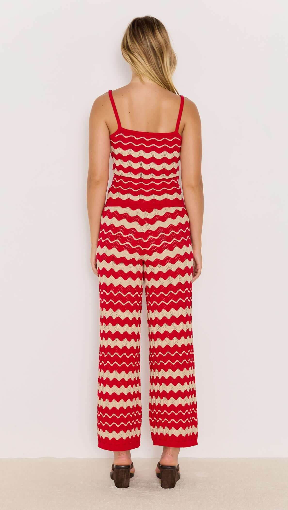 Model wearing red and beige wave stripe knit pants with relaxed leg and elasticated waist, shown from the back.
