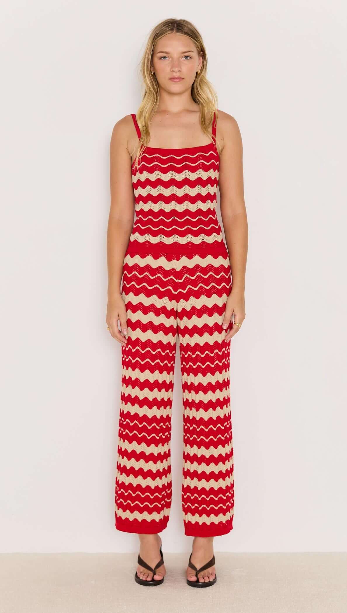 Model wearing wave stripe knit pants in red and beige with relaxed leg and elasticated waist, styled with a simple top.