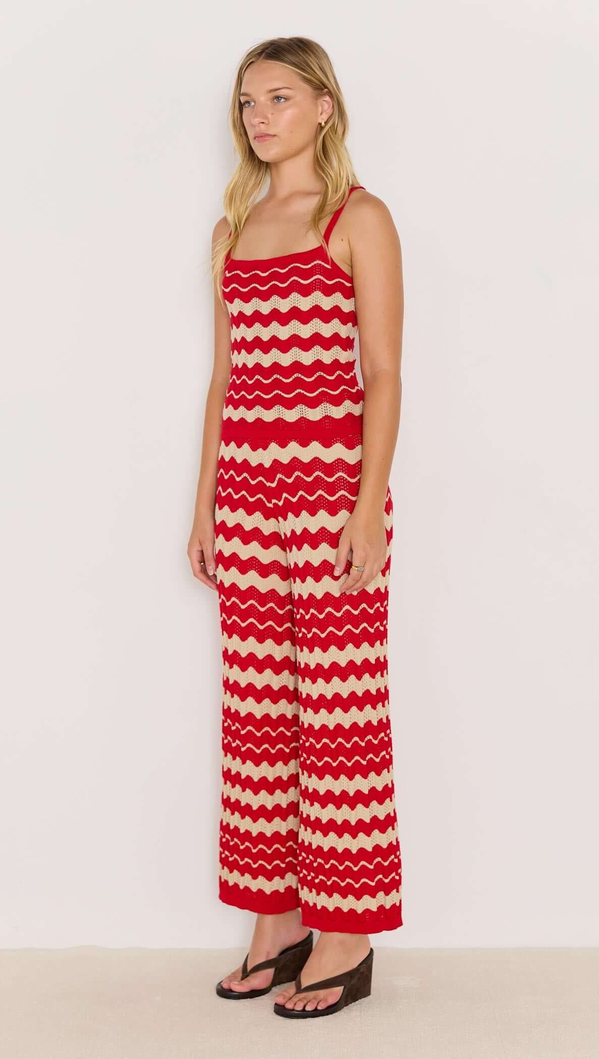 Woman wearing wave stripe knit pants in red and beige with a relaxed leg and elasticated waist.