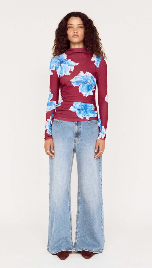 Model wearing a blue floral mesh long sleeve top with wide-leg jeans, showcasing a stylish outfit.
