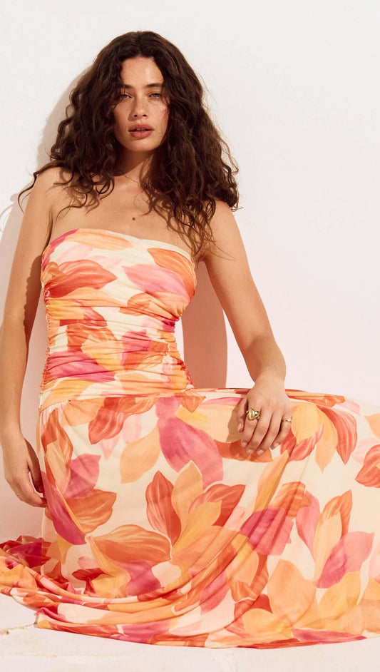 Sunset Leaf Print Sleeveless Midi Dress showcased by a model with curly hair in a tropical floral pattern.