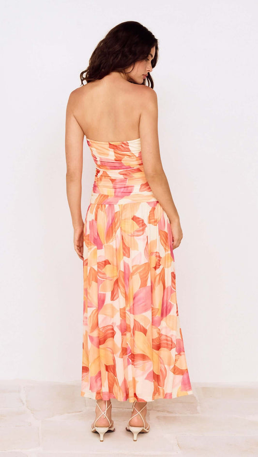 Back view of a model wearing a Sunset Leaf Print Sleeveless Midi Dress with vibrant tropical colors.