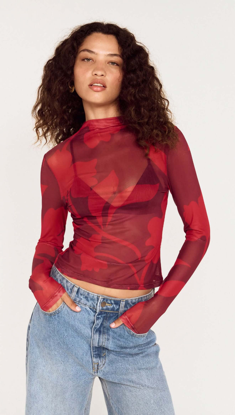 Model wearing an Oversized Floral High Neck Mesh Top in red floral print with long sleeves.