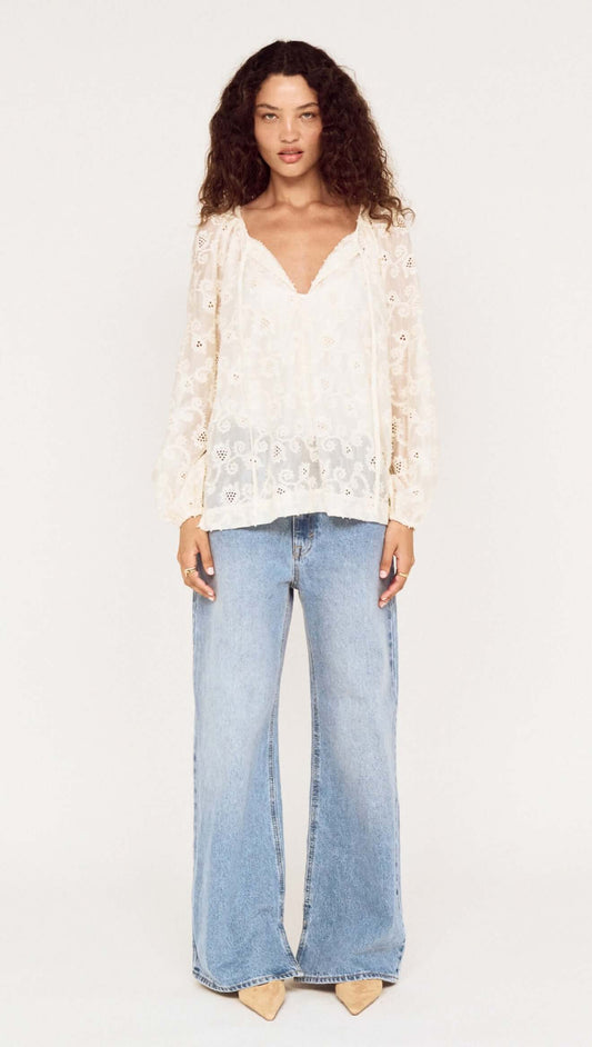 Model wearing the Cream Broderie Baloon Sleeve Blouse paired with flared blue jeans, showcasing its delicate design.