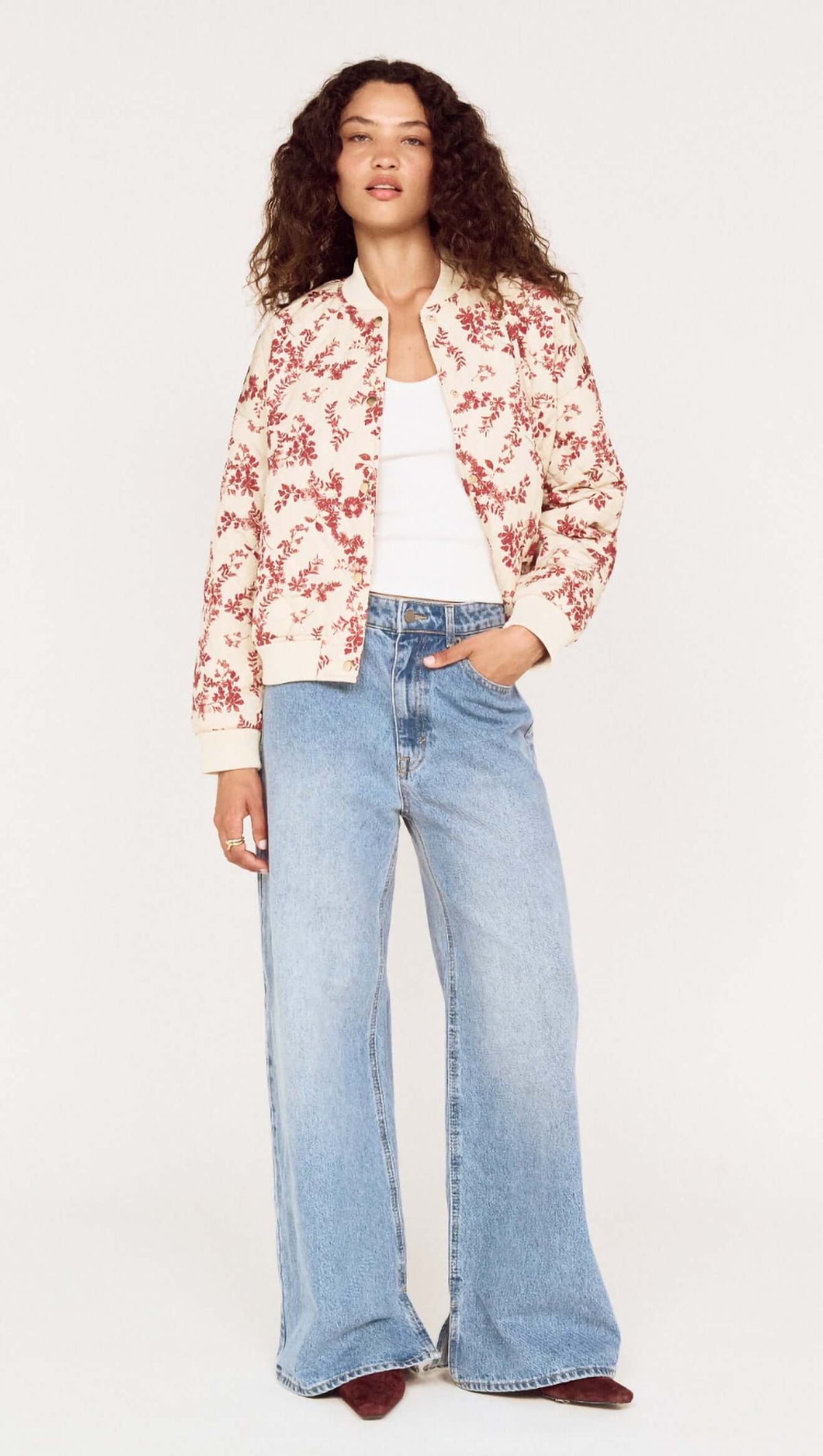 A woman wearing an Autumn Floral Quilted Puffer Jacket with wide-leg jeans, showcasing a stylish autumn look.