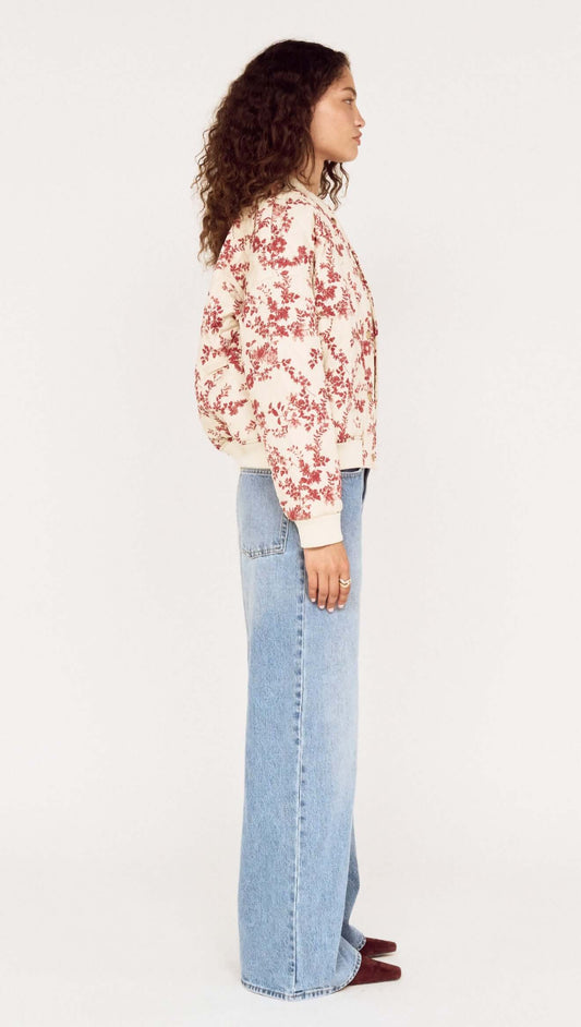 Side view of a model wearing an Autumn Floral Quilted Puffer Jacket with light blue jeans.
