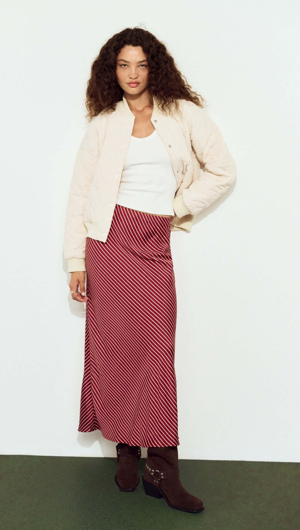 Model wearing a Quilted Bomber Jacket in Warm White paired with a striped skirt, showcasing a trendy outfit.