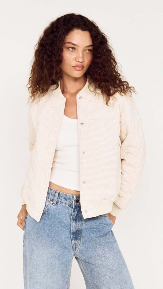 Quilted Bomber Jacket in Warm White worn by model with curly hair, featuring snap button closures and ribbed trims.