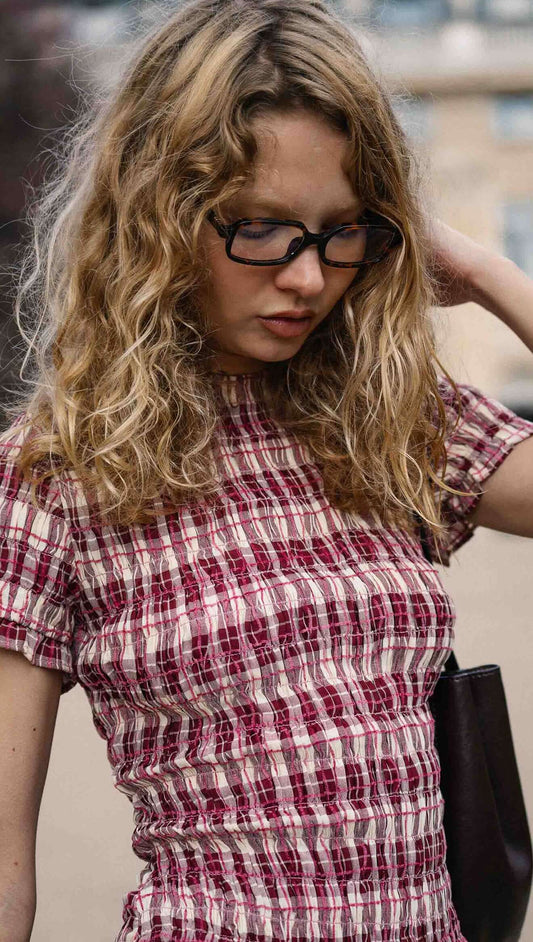 Model wearing a Short Sleeve Shirred Check Midi Dress with a textured fabric, showcasing feminine style and vintage vibes.