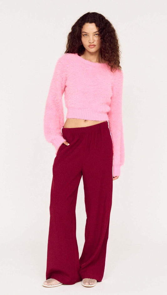 Model wearing the Clio Cropped Fuchsia Pink Fluffy Jumper with wide-leg pants, showcasing a stylish and cozy outfit.