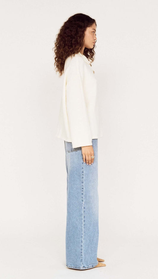 Model showcasing the Gold Detail Relaxed Polo Knit from the side, highlighting its relaxed fit and soft knit fabrication.