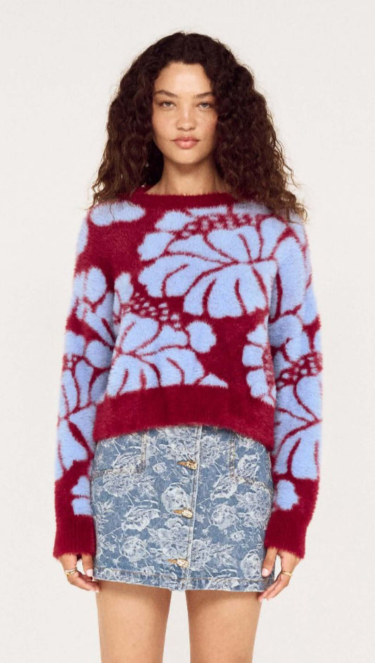 Model wearing Intarsia Floral Soft Touch Jumper in red and blue with floral design paired with a denim skirt.