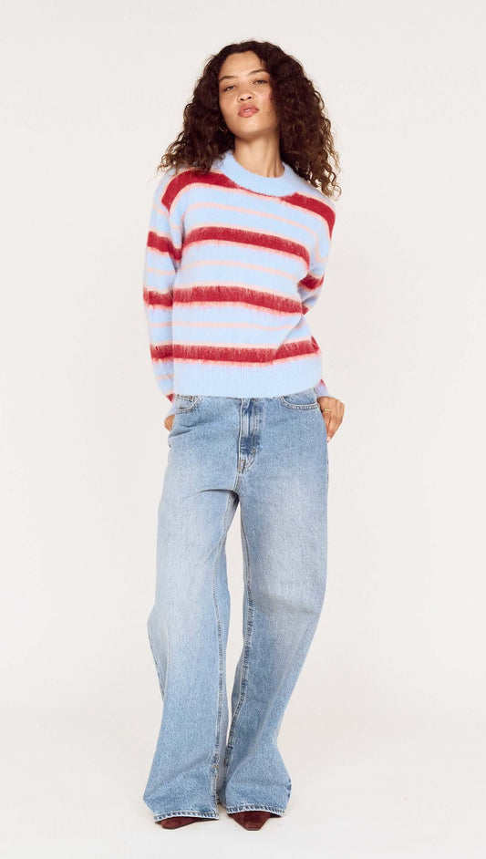 Model wearing a Peppermint Stripe Fluffy Jumper with red and blush stripes over a soft blue base, paired with denim.