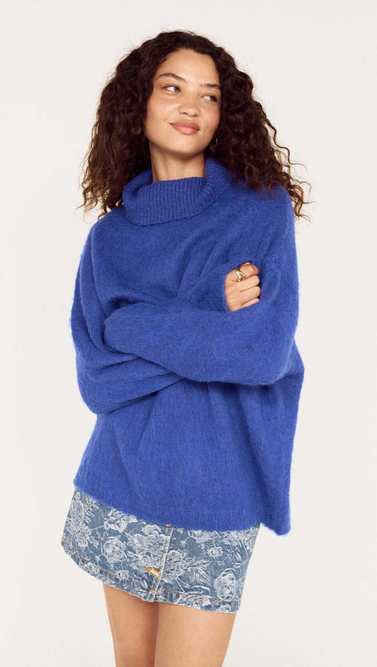 Model wearing a Blue Oversized Roll Neck Jumper, styled casually with a denim mini skirt.