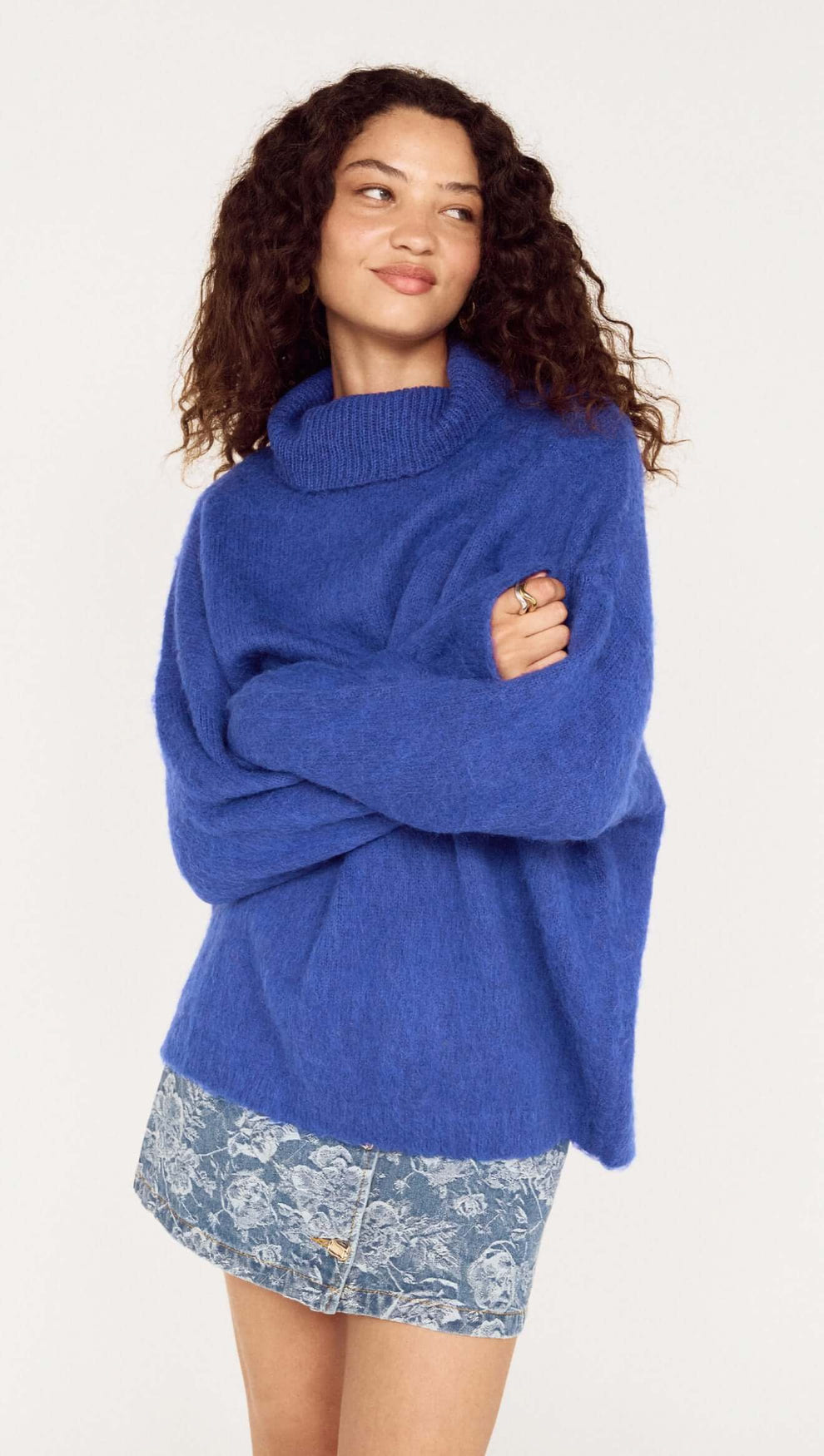Model wearing a Blue Oversized Roll Neck Jumper, styled casually with a denim mini skirt.