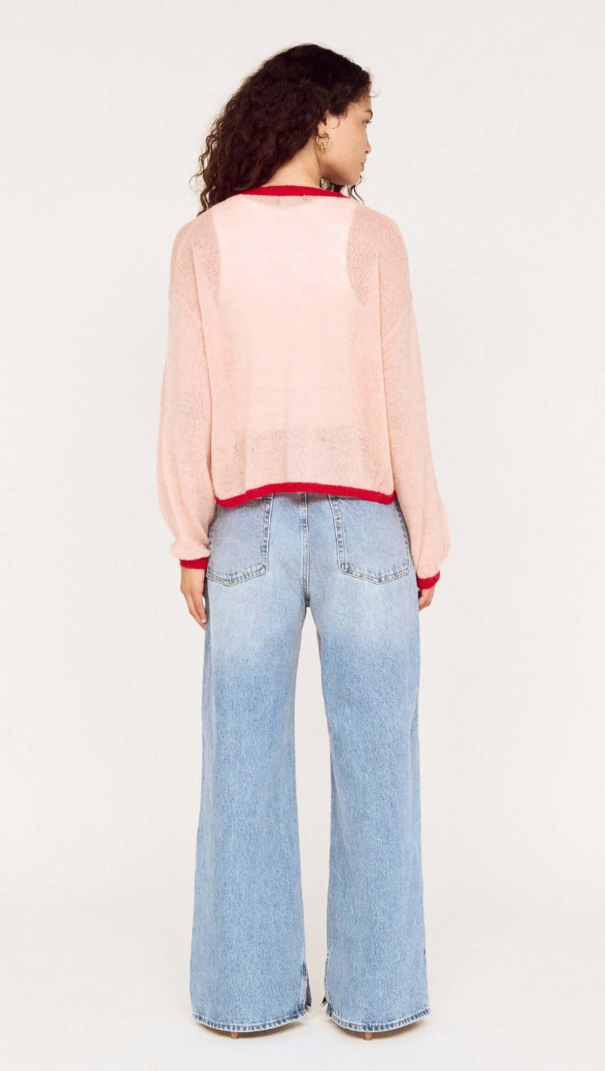 Back view of a model wearing the Sheer Contrast Trim Pink Cardigan with wide-leg jeans.