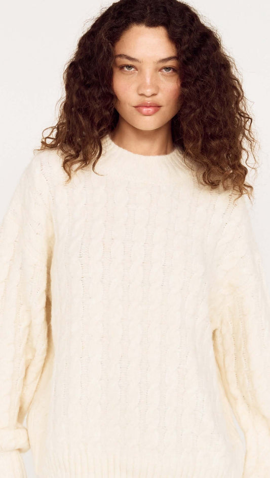 Cream Relaxed Fit Cable Knit Jumper worn by a model, showcasing its relaxed silhouette and classic crew neckline.