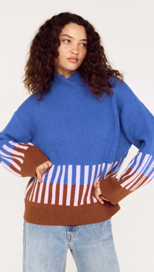 Model wearing a cobalt blue intarsia detail jumper with playful patterns in brown and pink.