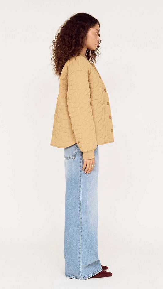Model wearing a side view of a Beige Floral Quilted Puffer Jacket with light blue jeans.