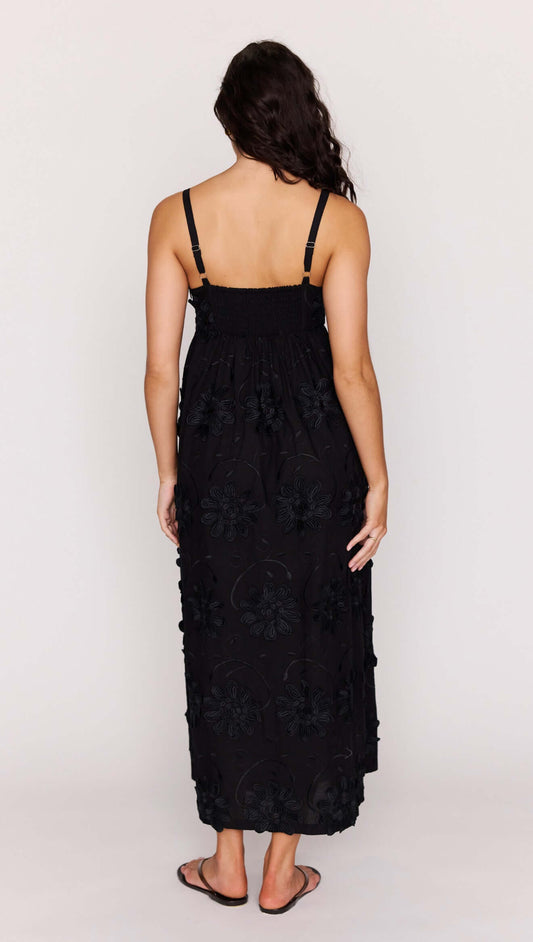 Back view of a woman wearing a Black Tiered Cotton Applique Midi Dress with floral detailing.