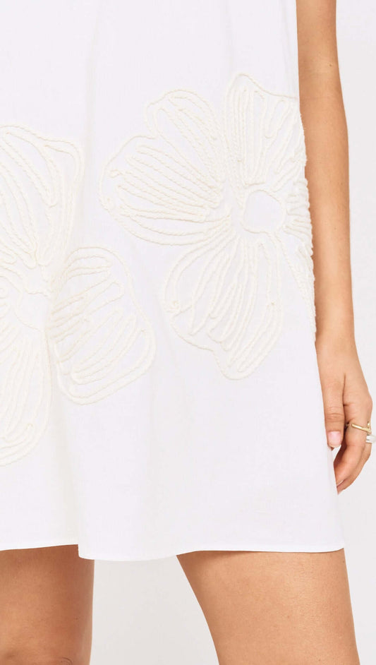 Close-up of Broderie Anglaise Cotton Mini Dress featuring beige floral embroidery on a white fabric.
