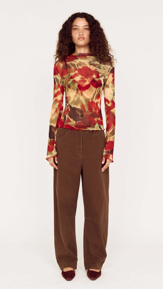 Model wearing brown mid rise barrel leg jeans with floral long-sleeve top, showcasing a modern fashion look.