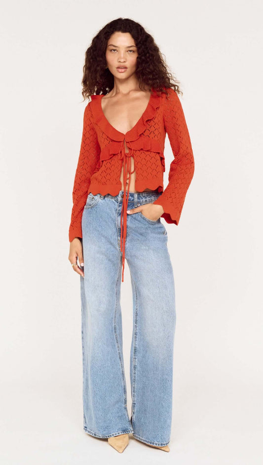 Model wearing a burnt orange pointelle tie front top paired with light blue wide-leg jeans.