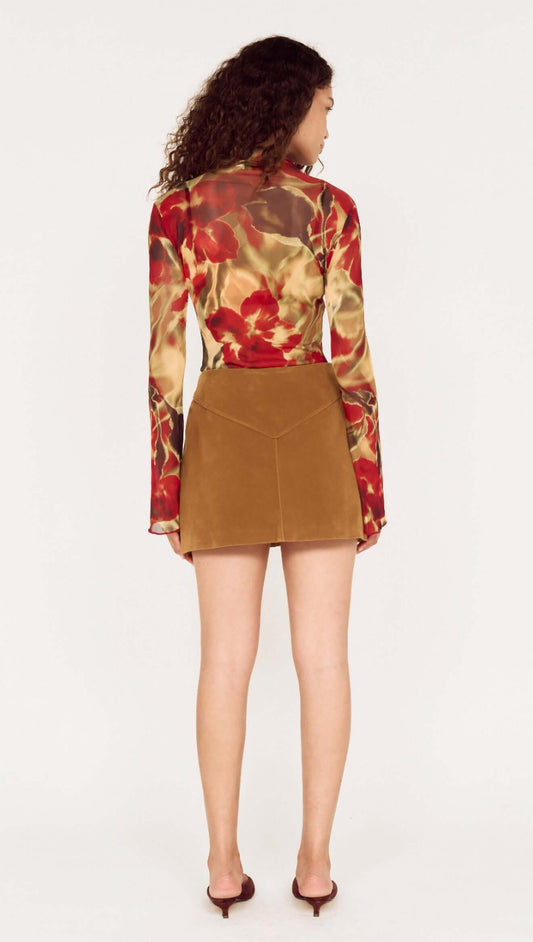 Back view of model wearing a Button Front Faux Sude Mini Skirt styled with a floral long-sleeve top.
