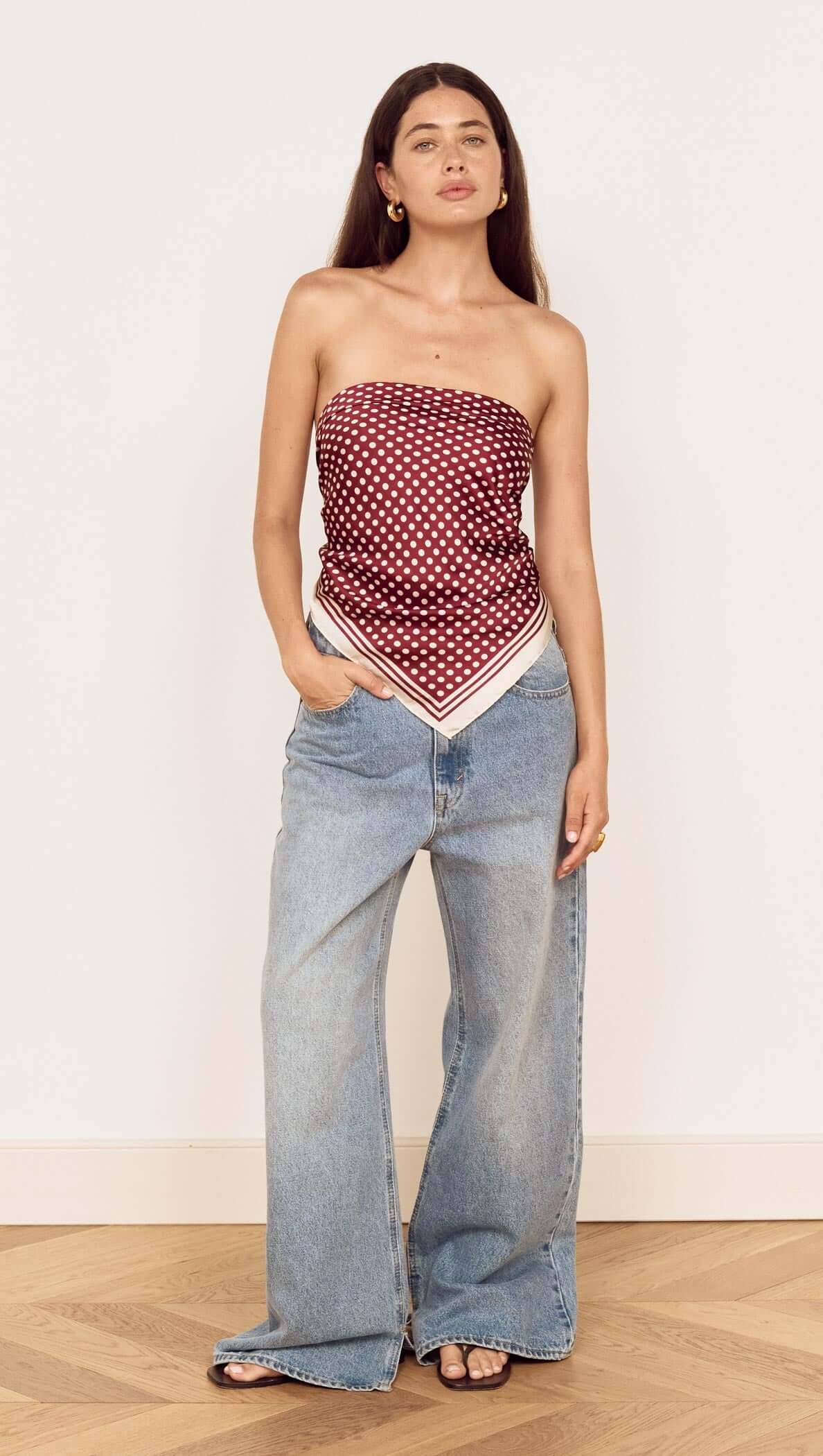 Model wearing Chocolate Polka Dot Scarf as a bandeau top with wide-leg jeans.