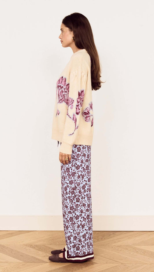 Model wearing a Cream Floral Intarsia Knit Sweater with floral design, styled with printed pants.